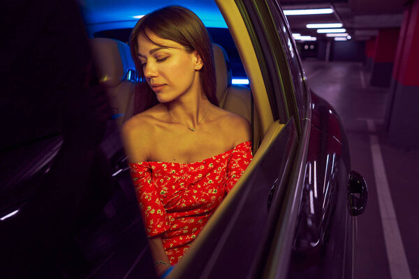Woman sitting on back seat in car at night