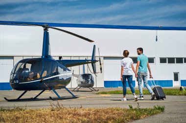 Romantik turist çift iniş yapan helikoptere doğru ilerliyor.