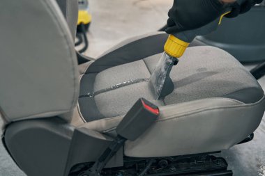 Uzman kuru temizlemeci araba koltuğunu kaldırdı. Tamirci süpürge kumaşı.