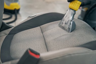 Otomatik servis süpürgesi ön koltuğu çamaşır makineli tüfeğiyle temizliyor.