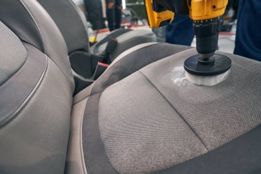 Araba servisi koltuğu fırçayla temizliyor.