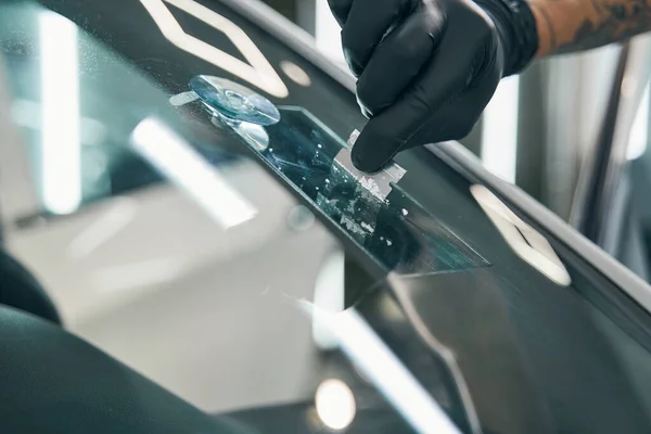 Überschüssigen Klebstoff abschrubben, um kaputte Autoscheiben zu reparieren. Endgültiger Abzug — Stockfoto