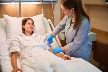 Kadın hasta hastane yatağında enjeksiyon tedavisi görüyor. Tıbbi konsept