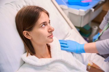 Hemşire hastane odasında hasta omzunu tutarak bakım gösteriyor. Tıbbi konsept