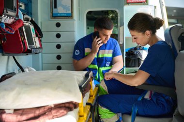 Sağlık görevlileri ambulanstaki tedavi detaylarını akıllı telefon konuşmalarıyla not ediyor. Tıbbi konsept