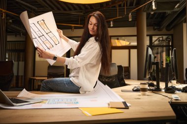 Beyaz bluzlu genç serbest çalışan biri, bir konferans odasında, iç mekanda, şık bir iç mekanda çizimler yapıyor.