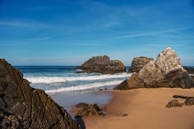 Praia da Adraga 'daki kumlu sahilden dramatik kaya oluşumları yükseliyor. Seyahat, manzara konsepti