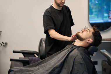 Profesyonel berber portresi, yanında duran, küçük jilet tutan ve kuaförde sakal tıraşı olan.