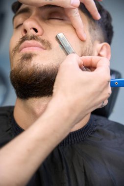 Traş makinesinin yakın fotoğrafını çek, erkeğin yanında dur, ustura ile sakal tıraşı ol.