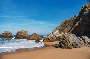 Altın kumlar, fısıldayan dalgalar ve yükselen uçurumlar, Praia da Adraga. Seyahat, manzara konsepti