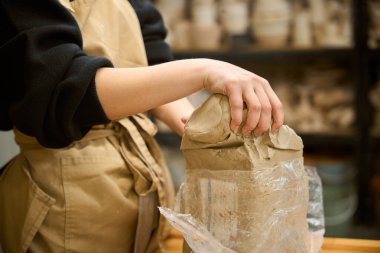 Bir seramik atölyesinde, elinde bir paket kille çalışan bir zanaatkar.