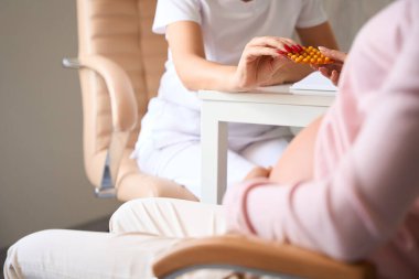 Tanımlanamayan hamile kadın klinikte doktoru ziyaret ediyor.