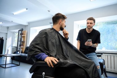 Moda berber dükkanındaki yetenekli berber danışmanlarına telefonda saç kesimi seçenekleri gösteriliyor