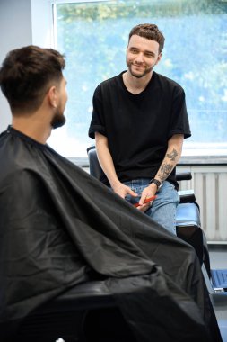 Yetenekli berber, modern berber dükkanındaki özel saç stili tercihlerini dinleyerek, erkeklerle detaylı bir istişare içine girer.