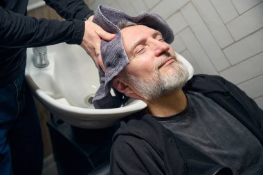 Berber dükkanında yıkandıktan sonra kuaför portresi erkek müşterinin kafasını havluyla siler. Saç kesimi, müşteri hizmetleri konsepti