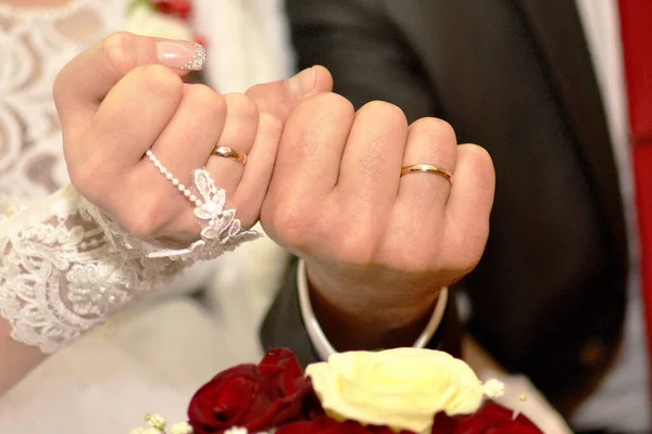 fists of the newlyweds with golden wedding rings