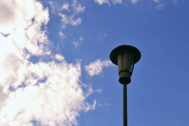 Beyaz bulutlu mavi gökyüzünün arka planında paslı eski bir fener.