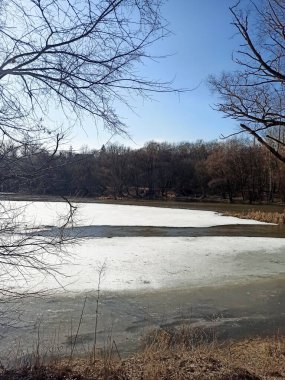 Nehirde eriyen beyaz buz, mavi bahar gökyüzüne karşı.