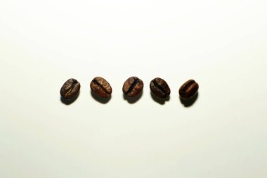 Kızarmış kahve çekirdekleri beyaz arka planda izole edilmiş.