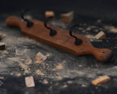 Kumaş askısı siyah bir arkaplanda izole edilmiş. Paslanmaz çelik kancalar eski ve klasik asma kıyafetleri ya da bağlı olan şeyler için. Kaliteli palto askıları ahşap bir plakaya asılmış. ahşap kanca