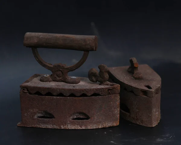 Old rusty antique iron for ironing clothes with the help of charcoal. Household antiques. Iron for clothes made of traditional steel with a wooden handle (Ayam Jago). Detailed photo of an old iron.