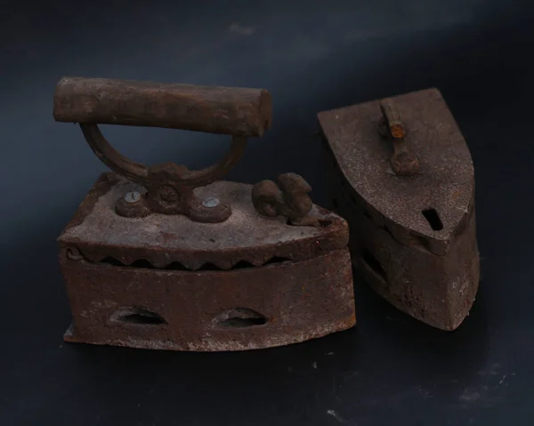 Old rusty antique iron for ironing clothes with the help of charcoal. Household antiques. Iron for clothes made of traditional steel with a wooden handle (Ayam Jago). Detailed photo of an old iron.