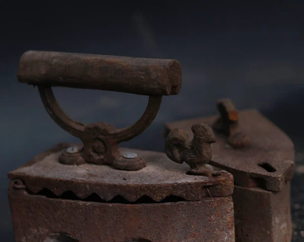 Old rusty antique iron for ironing clothes with the help of charcoal. Household antiques. Iron for clothes made of traditional steel with a wooden handle (Ayam Jago). Detailed photo of an old iron.