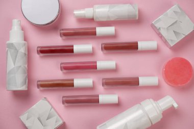 Gerçekçi dudak parlatıcısı seti. Dekoratif kozmetik ürünler için paketlerin bir kopyası. Fırçalı şişe, tüpler. Güzellik yüzü ve güzel dudaklar için makyaj. Resim güzellik ürünü makyajı pembeye izole edilmiş.