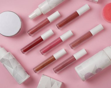 Gerçekçi dudak parlatıcısı seti. Dekoratif kozmetik ürünler için paketlerin bir kopyası. Fırçalı şişe, tüpler. Güzellik yüzü ve güzel dudaklar için makyaj. Resim güzellik ürünü makyajı pembeye izole edilmiş.