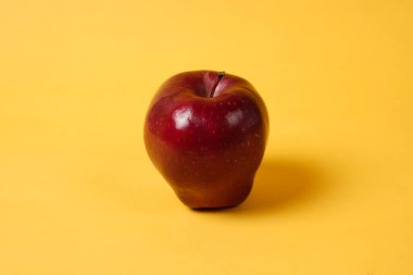 Parlak taze elmalar. Yan taraftan bak. Taze elma yerleştirme kavramı, genellikle tasarım şablonları ve modellemeler için kullanılan sarı bir arka planla birleştirilmiştir. Elmanın güzel şekli.