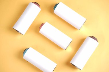 Farklı renklerde kapak uçları olan beyaz teneke kutular özgün bir kalıp oluşturmak için düzgün bir şekilde düzenlenmiştir. Sarı arka planda izole edilmiş eski kutular. Kullanılan kalay modeli.