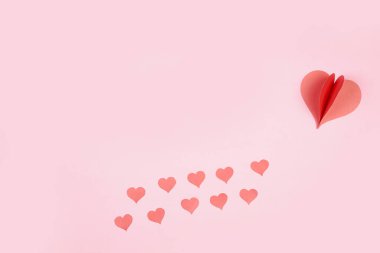 Pembe arka plana yapıştırılmış kalp şeklinde kağıt. Mutlu kadınlar için sevgi amblemi, sevgili anne, doğum günü kartları ve sevgililer günü selamlama tasarımları. Sevgililer Günü geçmişleri. Aşkımızı iletmek için şablonlar.