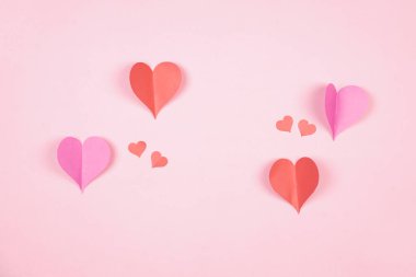 Pembe arka plana yapıştırılmış kalp şeklinde kağıt. Mutlu kadınlar için sevgi amblemi, sevgili anne, doğum günü kartları ve sevgililer günü selamlama tasarımları. Sevgililer Günü geçmişleri. Aşkımızı iletmek için şablonlar.