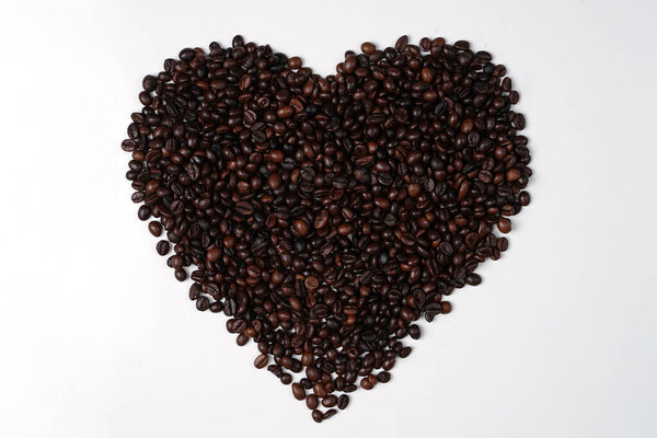 Handcrafted arrangement of coffee beans shaped to resemble a heart, symbol of love to commemorate Valentine's Day. Blend of coffee beans and symbol of love for the background concept.