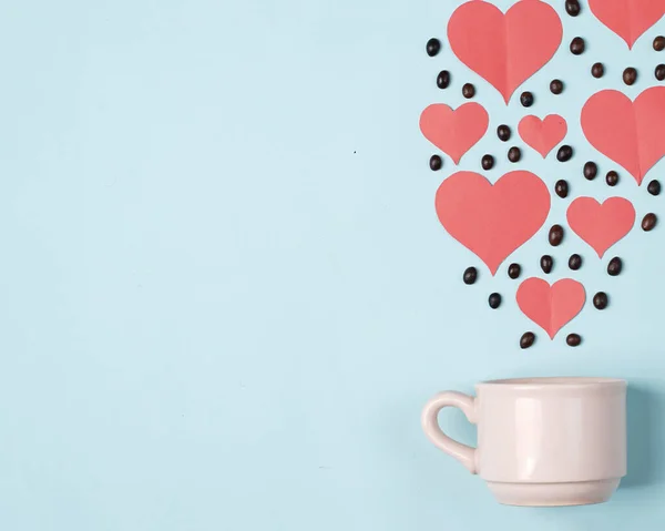Valentine\'s background concept with coffee lovers. Combination of a white cup with coffee beans and a heart shaped cut of paper. Template design. Let\'s celebrate Valentine\'s Day by enjoying coffee.
