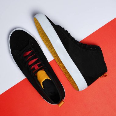 Siyah spor ayakkabılar kırmızı ve beyaz arka planda izole edilir ve kesilmesi kolay bir yol ile kesilir. Yüksek açılı spor ayakkabılar. Yüksek siyah ayakkabılar. İki renkli arka planda bir çift ayakkabı. Ayakkabılar yakın..