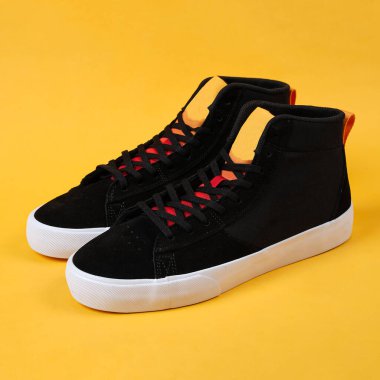 Spor ayakkabısı konsepti. Düz ayakkabılar sarı arka planda izole edilmiş. Moda ayakkabıları. Klasik spor ayakkabı. Retro siyah ayakkabılar. Unisex ayakkabıları, spor ayakkabısı arka planda izole edilmiştir.                 