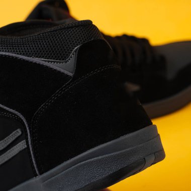 Sarı arka planda izole edilmiş bir çift siyah spor ayakkabısı. Siyah spor ayakkabı duvar kağıdı. Sarı arka planda siyah spor ayakkabıların modeli. Promosyon malzemeleriniz için uygun. Spor ayakkabılarını kapat