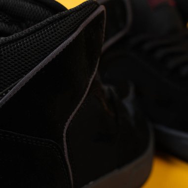 Sarı arka planda izole edilmiş bir çift siyah spor ayakkabısı. Siyah spor ayakkabı duvar kağıdı. Sarı arka planda siyah spor ayakkabıların modeli. Promosyon malzemeleriniz için uygun. Spor ayakkabılarını kapat