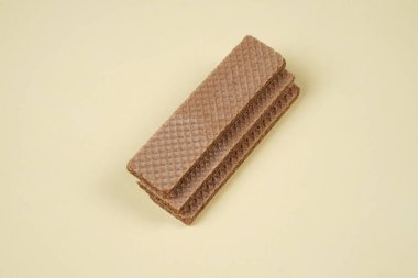 Sarı arka planda izole edilmiş rastgele bir yığın gofret. Çikolatalı bisküviler lezzetli kremalı çikolatalarla dolu. Kuru ve çıtır gofretler yemeye hazır. Güne bir gofretle başlamaya hazırım..