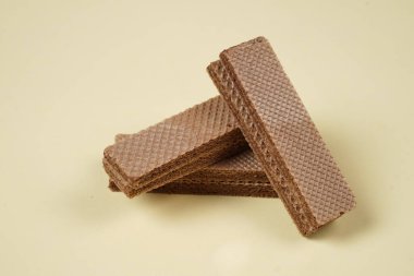 Sarı arka planda izole edilmiş rastgele bir yığın gofret. Çikolatalı bisküviler lezzetli kremalı çikolatalarla dolu. Kuru ve çıtır gofretler yemeye hazır. Güne bir gofretle başlamaya hazırım..