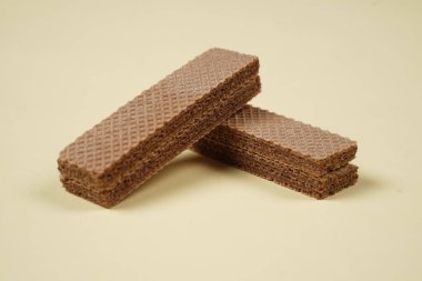 Sarı arka planda izole edilmiş rastgele bir yığın gofret. Çikolatalı bisküviler lezzetli kremalı çikolatalarla dolu. Kuru ve çıtır gofretler yemeye hazır. Güne bir gofretle başlamaya hazırım..