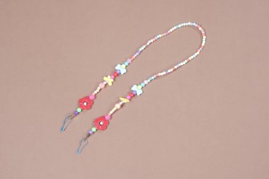 Kayıp ya da unutulmasın diye kumaş maskeyi boncuklu ya da elle örülmüş kayışlarla asmak. Sağlık maskesi takmamızı kolaylaştıran kayışlar. Boncuk kayışlar, el örgüsü kayışlar..    