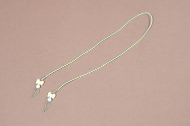 Kayıp ya da unutulmasın diye kumaş maskeyi boncuklu ya da elle örülmüş kayışlarla asmak. Sağlık maskesi takmamızı kolaylaştıran kayışlar. Boncuk kayışlar, el örgüsü kayışlar..    