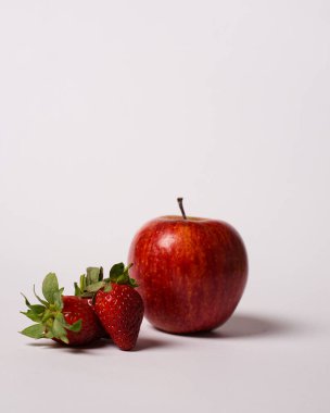 Beyaz arka planda izole edilmiş olgun elma ve çilekler. Taze meyve suyu için uygun C vitamini açısından zengin besleyici meyveler. Aktiviteye başlamadan önce sabahleyin yemeye hazır olun..