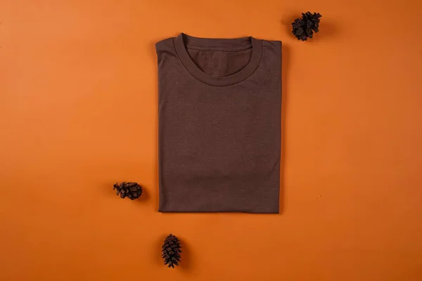 Plain brown t-shirt isolated on orange background adds to the elegant impression. T-shirts made of cotton are very comfortable for everyday wear. Empty space for your ad. T-shirt mockup.