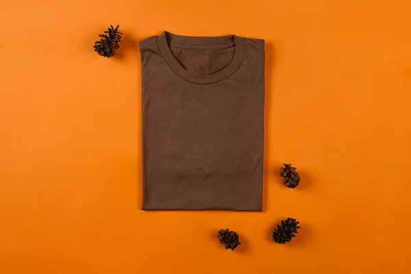 Plain brown t-shirt isolated on orange background adds to the elegant impression. T-shirts made of cotton are very comfortable for everyday wear. Empty space for your ad. T-shirt mockup.