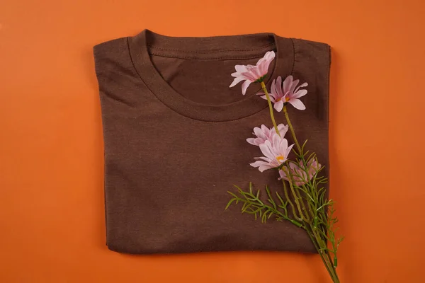 Plain brown t-shirt isolated on orange background adds to the elegant impression. T-shirts made of cotton are very comfortable for everyday wear. Empty space for your ad. T-shirt mockup.