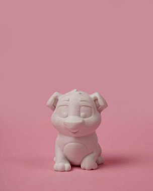 Poly laktik asitten yapılmış köpek yavrusu minyatürü. 3D baskı makinesi kullanılarak tasarlanmış. Yavru köpek pembe arka planda izole edilmiş. Minyatür model..