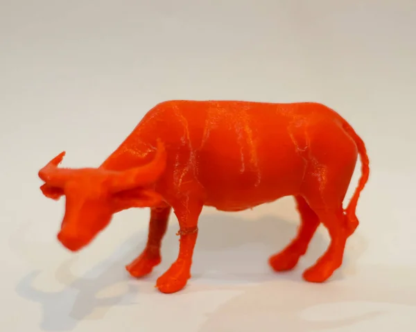 Cnc router in the shape of a red buffalo. 3D design made of plastic. Miniature animals are suitable to be used as collections or room furniture. Laser cutting. Laser templates. Focus blur.